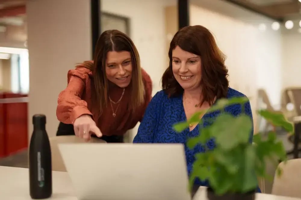 Two women smiling and looking at a laptop