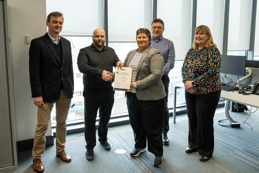 A group of five people being presented with an LCS certification